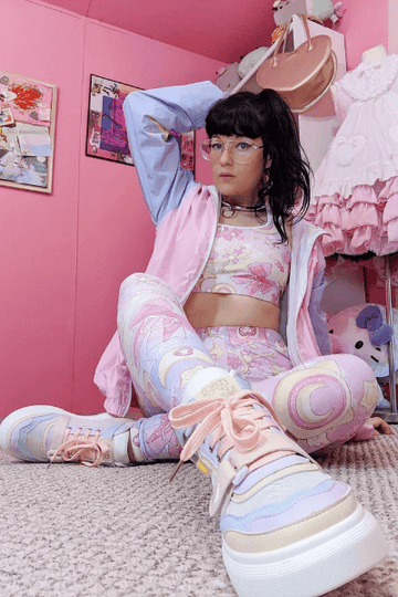Kawaii fashion enthusiast in pastel outfit seated on carpet surrounded by cute decor.