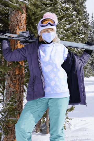 Woman enjoying skiing in stylish kawaii fashion outfit in a snowy landscape with ski gear and a playful pink hat.