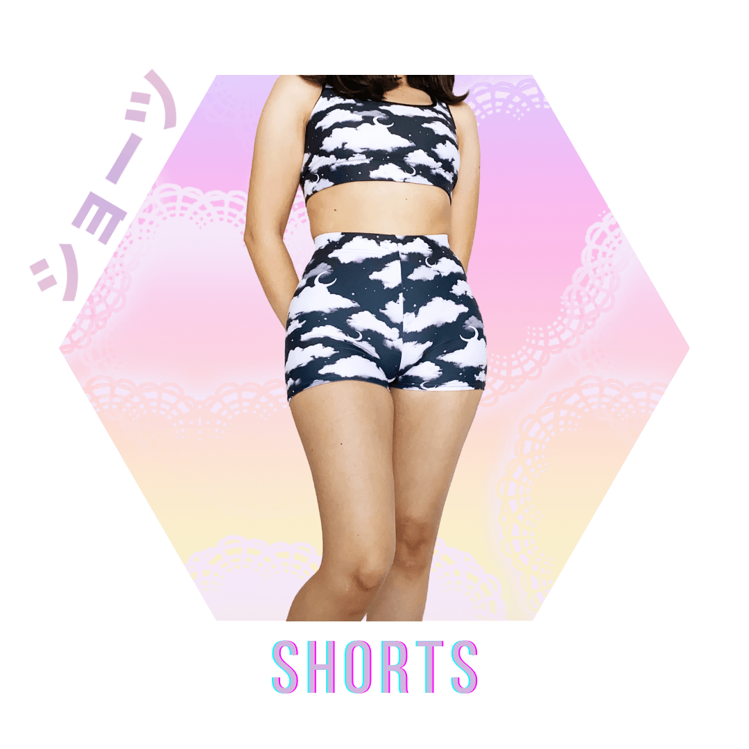 Model showcasing kawaii fashion with cloud print shorts and crop top against a pastel gradient background.